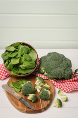 Fresh broccoli with spinach on wooden table close up