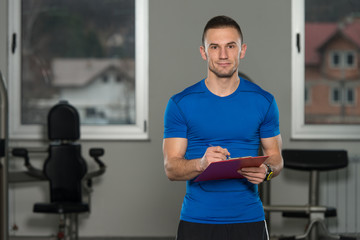 Personal Trainer Takes Notes On Clipboard