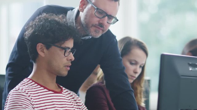 Teacher Talking with Students and Helping them in Computer Class. Shot on RED Cinema Camera in 4K (UHD).
