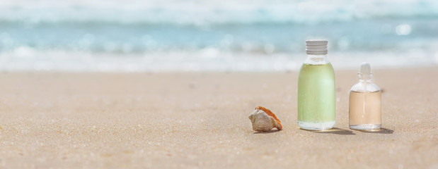 Bottles with oil essence and shell in the sea waves. Spa and wellness setting.