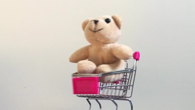 Mini metallic shopping cart turning around and teddy bear