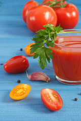 Tomato juice and vegetables with spices on blue board, healthy nutrition