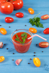 Tomato juice and vegetables with spices on blue board, healthy nutrition