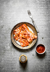 Fried bacon with tomato sauce and salt.