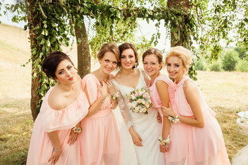 Stunning bridesmaids pose around beautiful bride outside