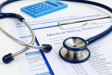 Stethoscope on medical bills and health insurance claim form