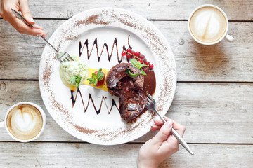 Sweet dessert and coffee on the wooden table with hands