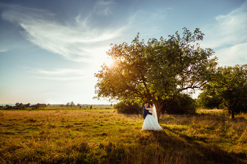 Light clouds fly on the sky under which wedding couple stands