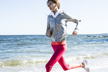 Slender woman running a sandy beach
