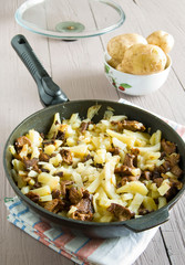 fried potatoes with mushrooms in a frying pan