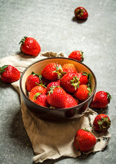 Ripe strawberries in bowl on old fabric.