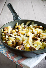 fried potatoes with mushrooms in a frying pan