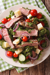 Sliced beef steak with a salad of fresh vegetables close-up. Vertical top view
