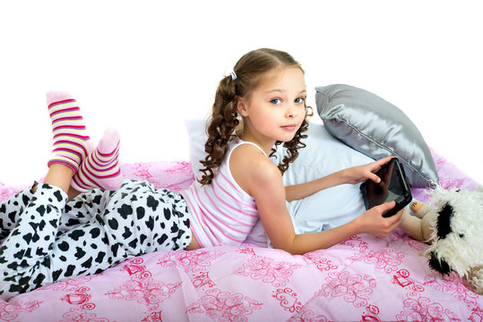 happy little girl lying on bed with tablet computer - Powered by Adobe