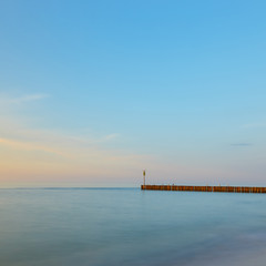 Fototapeta na wymiar sunset on the beach with a wooden breakwater, long exposure