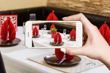 Woman photographing on smartphone, interior of modern restaurant