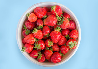 bowl full of strawberries on blue table