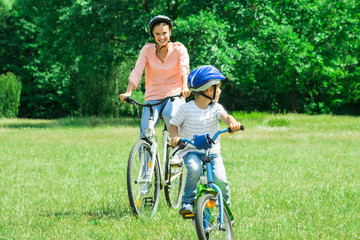 Fototapeta premium Mother And Son Are Cycling In The Park