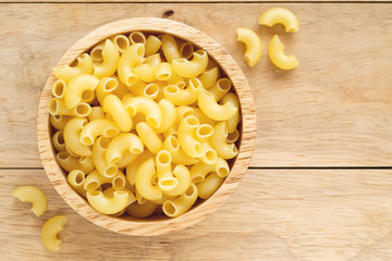 elbow macaroni in wooden bowl.
