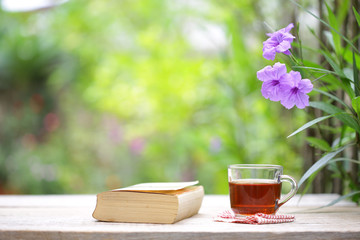 Tea glass and notebook on wooden table at outside