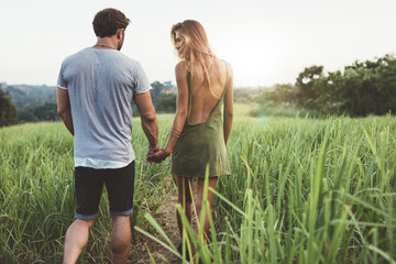 Young couple walking through grassy road