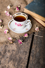 Vintage teapot and cup with blooming tea flowers on wooden background
