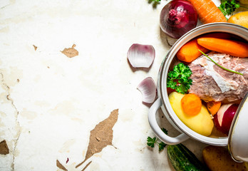 Soup with vegetables, pork, spices and herbs in a saucepan.