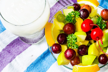 Bowl of healthy fresh fruit salad and milk on pattern of Thai hand made fabric background