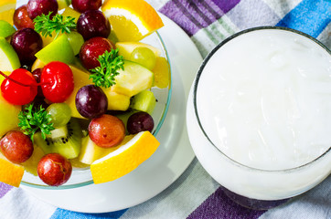 Bowl of healthy fresh fruit salad and milk on pattern of Thai hand made fabric background