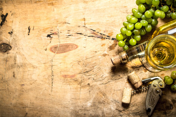 Bunch of white grapes with wine, a corkscrew and stoppers.