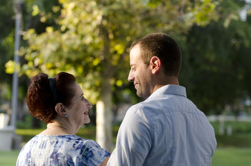 Obraz premium Cherishing mother son bond. Mother and her adult son walking in a park on a fall evening stopping to take in the moment.