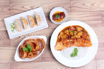 Rice with deep fried dolly fish in japanese yellow curry served with side dish of gyoza and onion ring on white background.