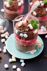 Layered chocolate, berry and chia seeds mousse dessert on black background, selective focus