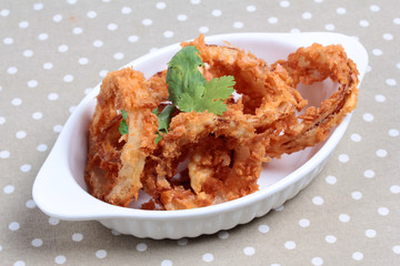 Dish of fried onion rings on gray. Selective focus
