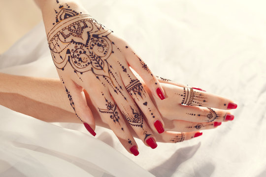 Red manicured hands with Mehndi