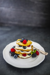 Delicious homemade pancakes with fresh ripe berries served on white plate on stone background.
Space for text.