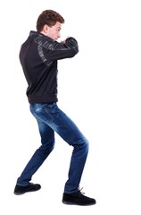 Naklejka premium back view of guy funny fights waving his arms and legs. Curly guy in a black leather jacket fights waving his arms.