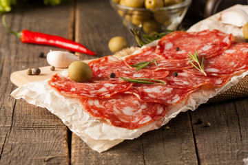 Chorizo sausage and salami, thin cut. spanish salami on the wood background with spices, paprika, pepper. Spicy food. Chili.