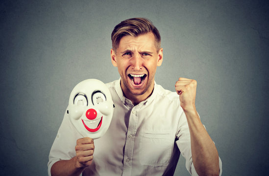 angry screaming man holding clown mask expressing cheerfulness happiness