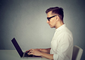 Side profile young man using a laptop computer