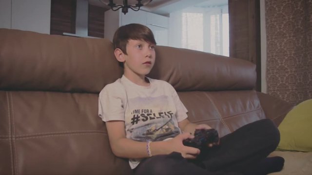 Boy playing video games on the console the on the sofa at home