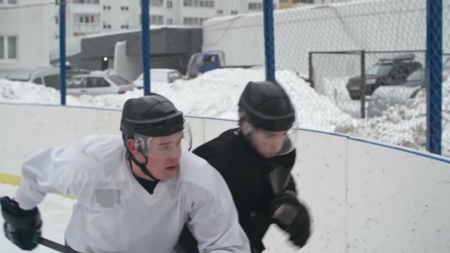 Slow motion tracking of tough ice hockey forward player using body-checking and bordering dribbling grinder from opposing team 