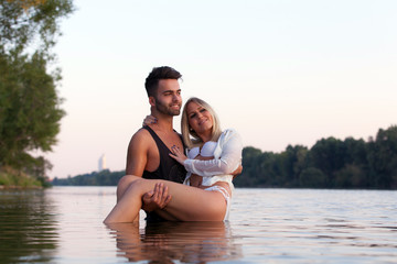 Handsome man carrying his girlfriend in a river