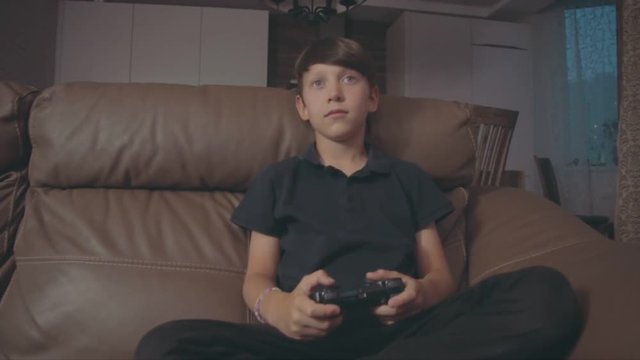 Boy playing video games on the console the on the sofa at home