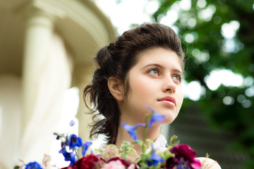 Naklejka premium Beautiful young woman with flowers in garden summer house