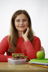 Back to school. Teenage girl with healthy food in a lunch box on white background. 