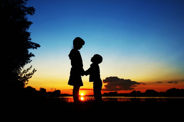 Fototapeta na wymiar Happy children silhouettes on sunset background