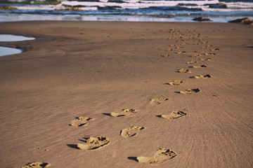 Footprints in the sand on Polzeath beach Vintage Retro Filter.