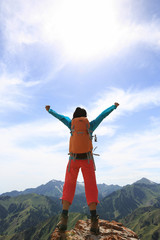 cheering young woman hiker open arms on mountain top