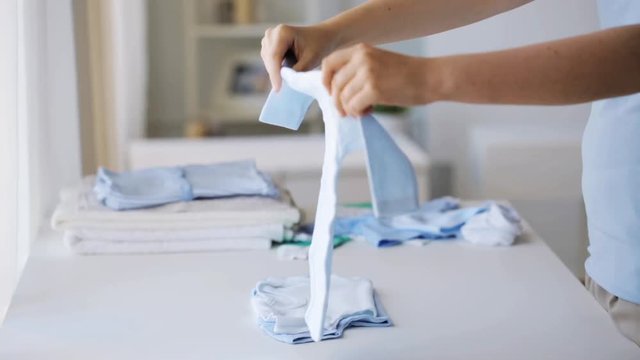 pregnant woman folding baby boys clothes at home 26